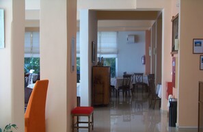 Un coin repas comprenant une table et des chaises, un meuble en bois et une fenêtre avec des stores.