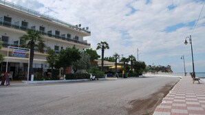 Un edificio frente al mar con letrero de restaurante, un camino pavimentado y palmeras.