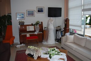 Un salon avec un piano, un téléviseur fixé au mur et un canapé blanc.