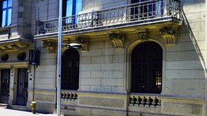 A historic building with a balcony, large windows, and a street lamp.