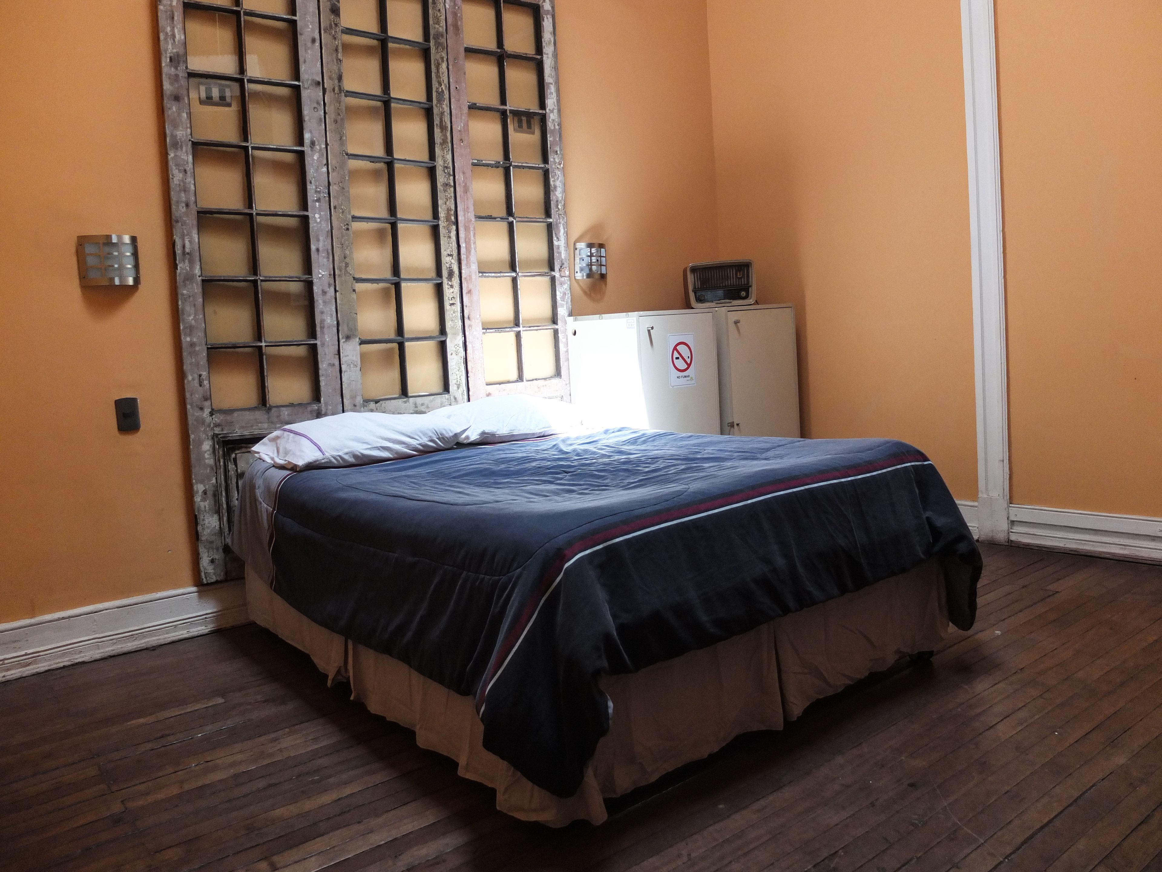 A room with a bed, a wardrobe, and a window with a grid pattern.