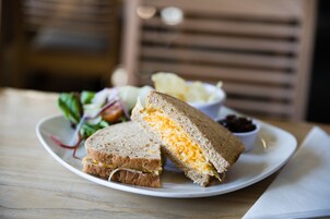 Een bord met een door midden gesneden sandwich, een klein schaaltje saus en een salade.