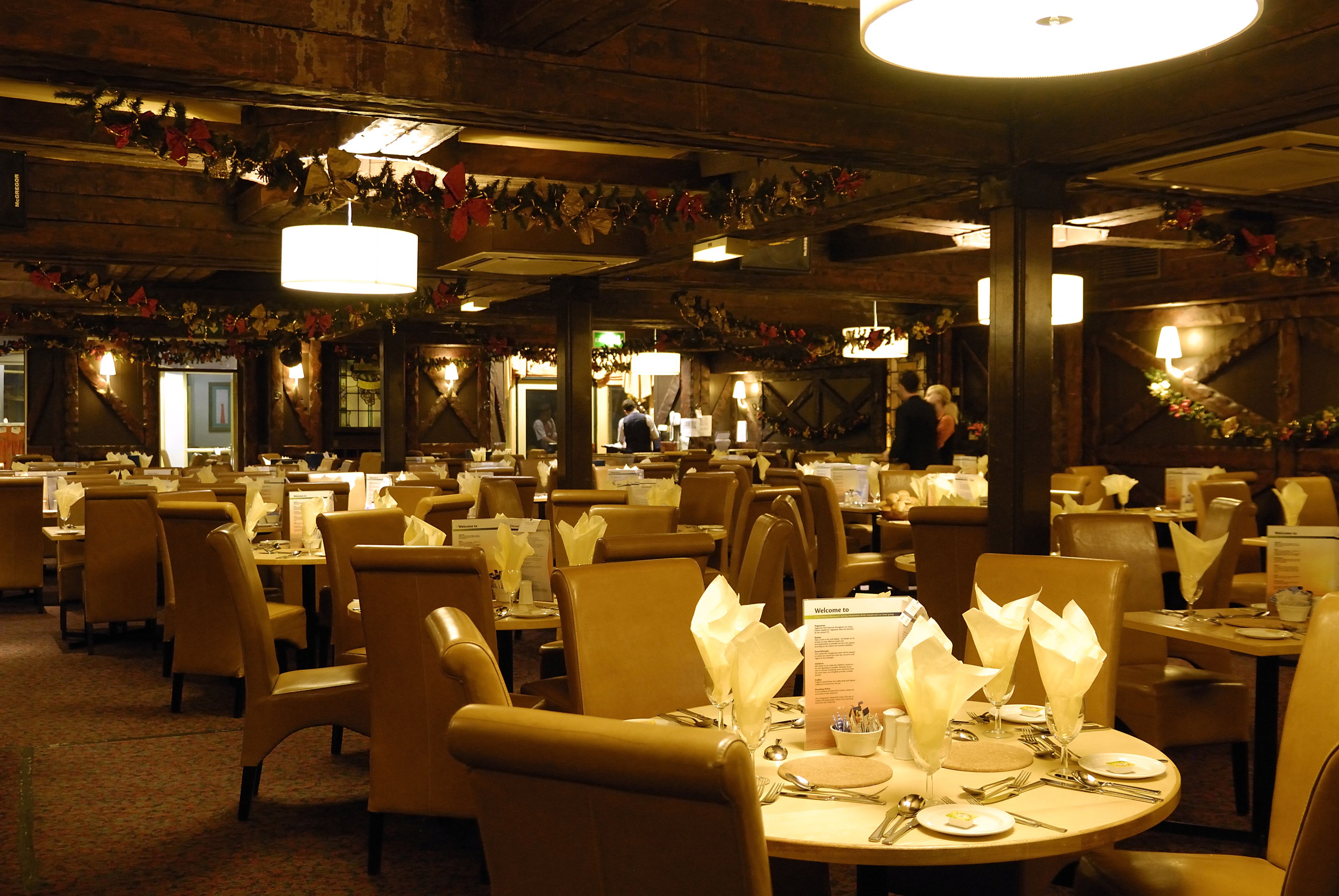Ein Restaurant mit runden Tischen, Stühlen und einer warmen, gedämpften Beleuchtung.