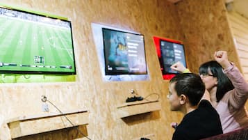 Een kamer met houten wanden, een groot scherm waarop een voetbalwedstrijd wordt vertoond en een kleiner scherm met een film.