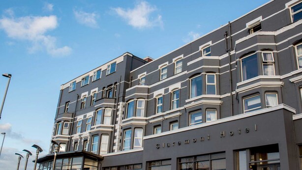 Ein mehrstöckiges Hotel mit dunkler Fassade und weißen Akzenten an Fenstern und Ecken.