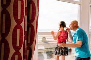 Een kamer met een groot raam met uitzicht op een strand.