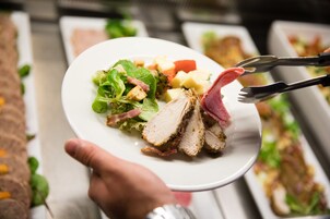 A plate with sliced meat, vegetables, and a salad.