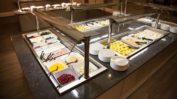 A buffet with various food items and utensils.