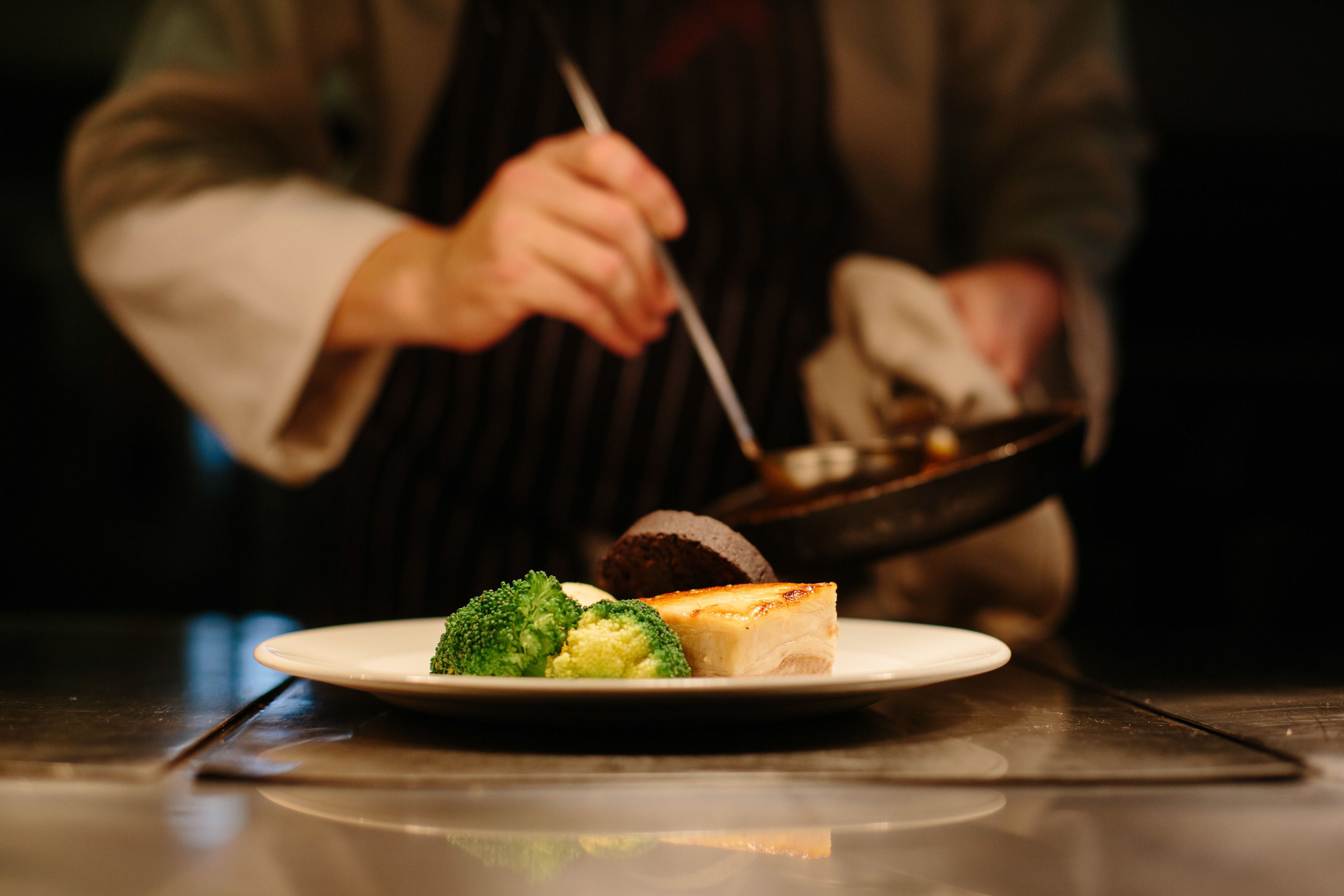 Een bord met een stuk cheesecake en broccoli op een tafel.