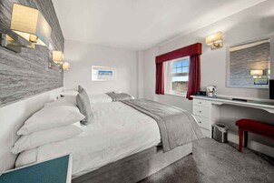 Een moderne hotelkamer met een groot bed, een bureau en uitzicht op de omgeving.