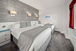 Cortinas opacas, tabla de planchar con plancha, ropa de cama