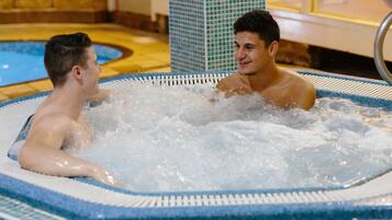 Relax in a hot tub surrounded by a tiled floor and a window with an outdoor view.