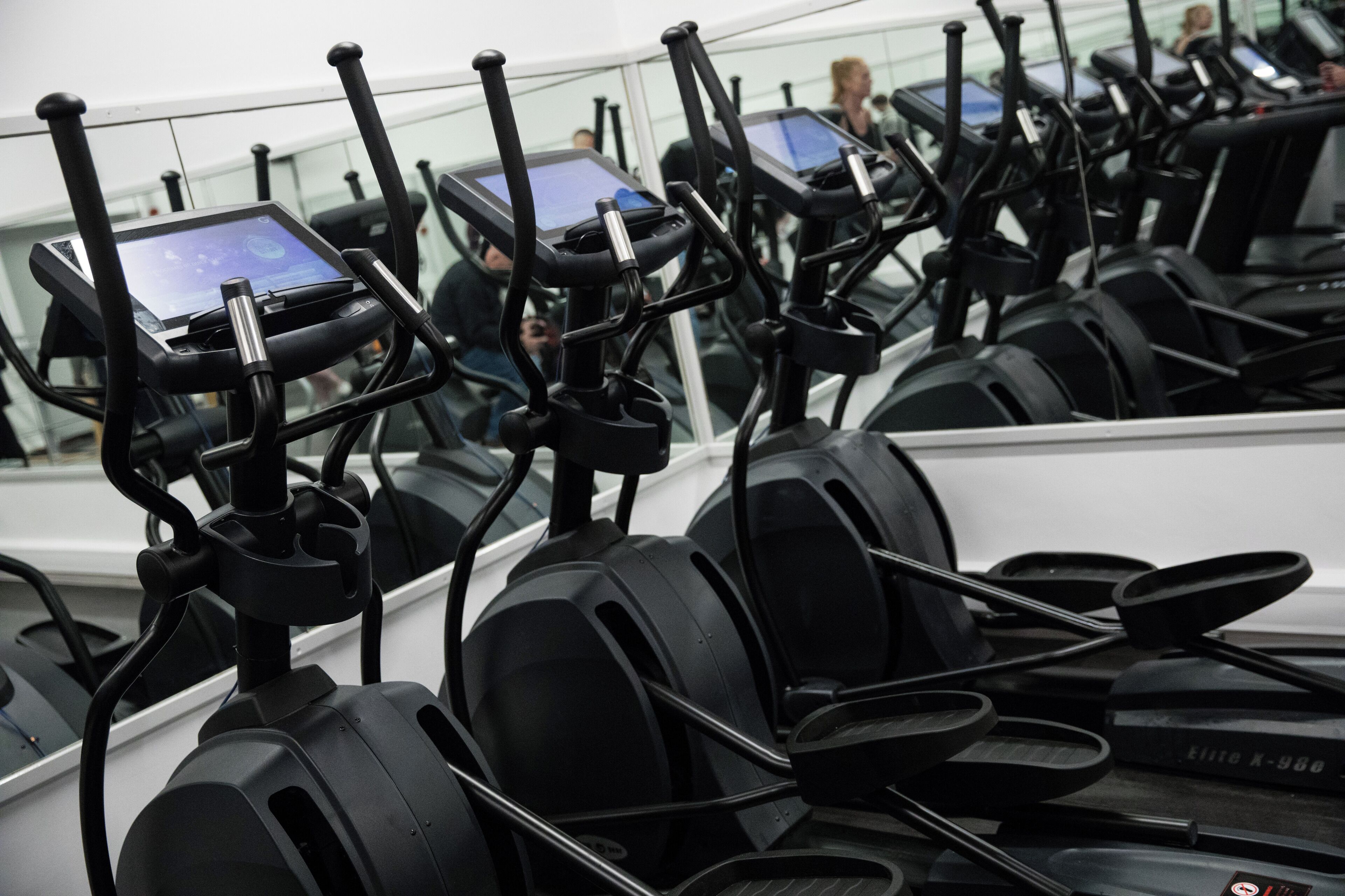 Een rij stilstaande fietsen met digitale schermen, waarschijnlijk in een sportschool of fitnesscentrum.