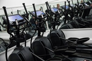 Een rij stilstaande fietsen met digitale schermen, waarschijnlijk in een sportschool of fitnesscentrum.