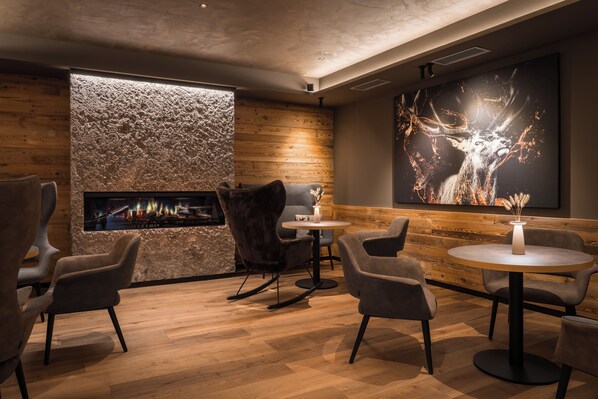 A modern interior with a fireplace, seating area, and a large artwork on the wall. - Hotel Crozzon (Pinzolo)