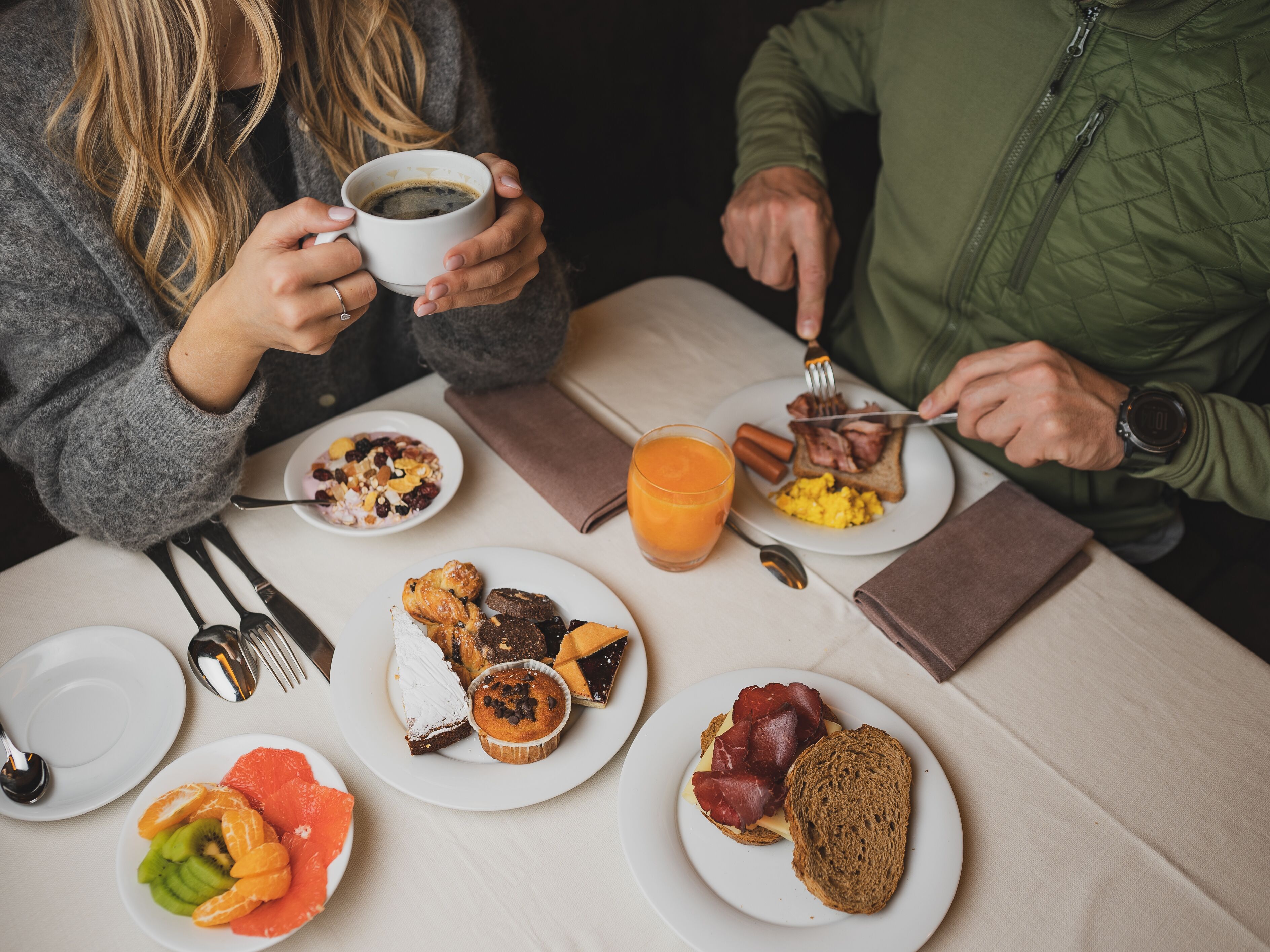 A breakfast setting with plates of food, a cup of coffee, and a glass of orange juice.