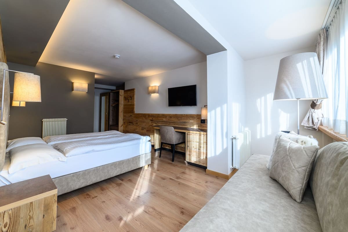 A modern hotel room with a large bed, a desk, and a TV.