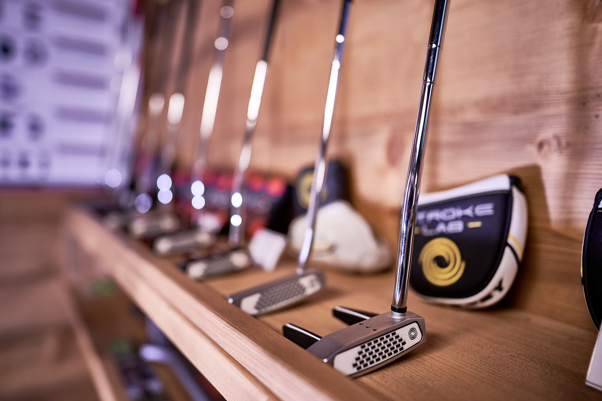 A row of golf clubs on a wooden rack.