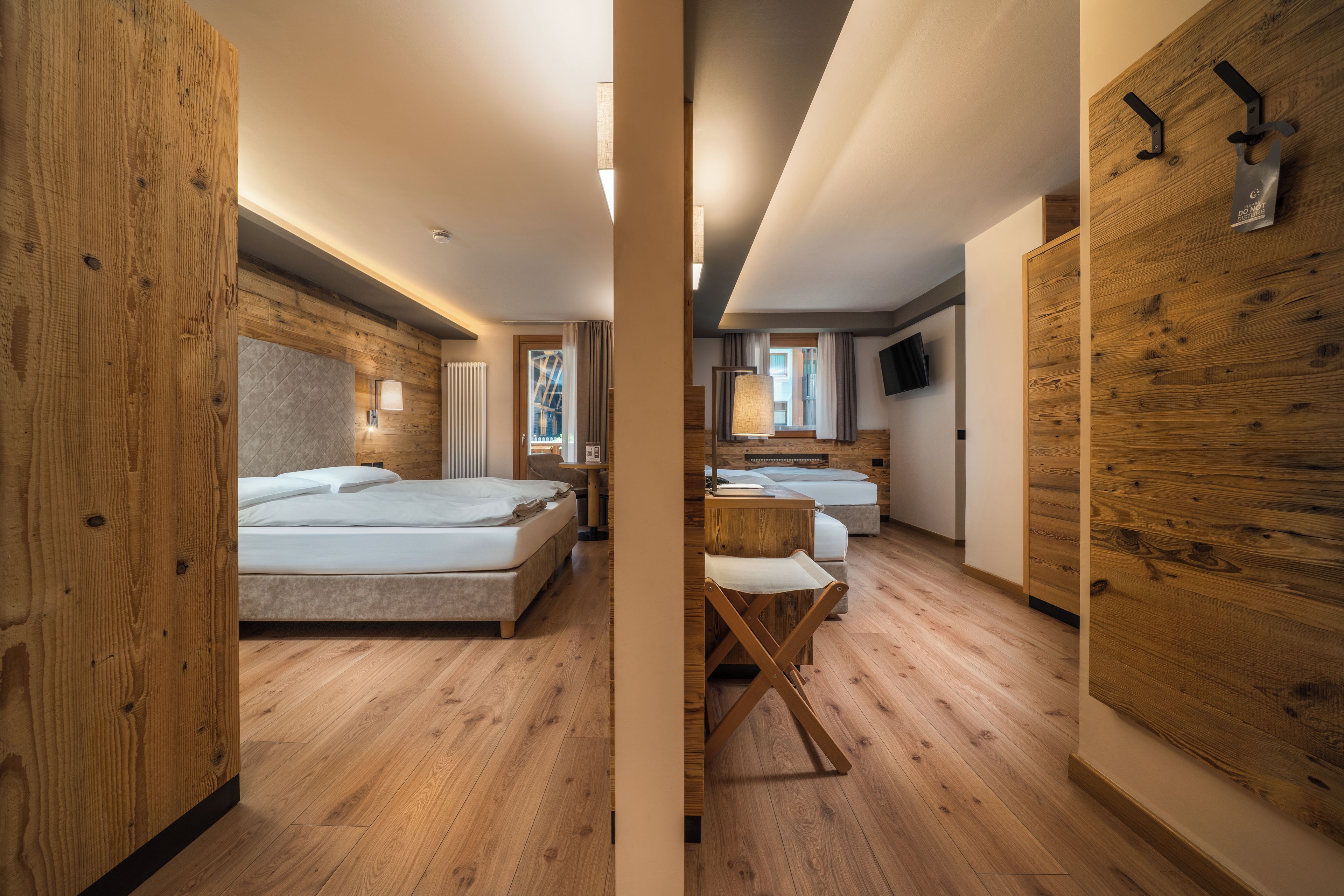 Una moderna camera d'albergo con pavimento in legno, un letto, una scrivania e un televisore.