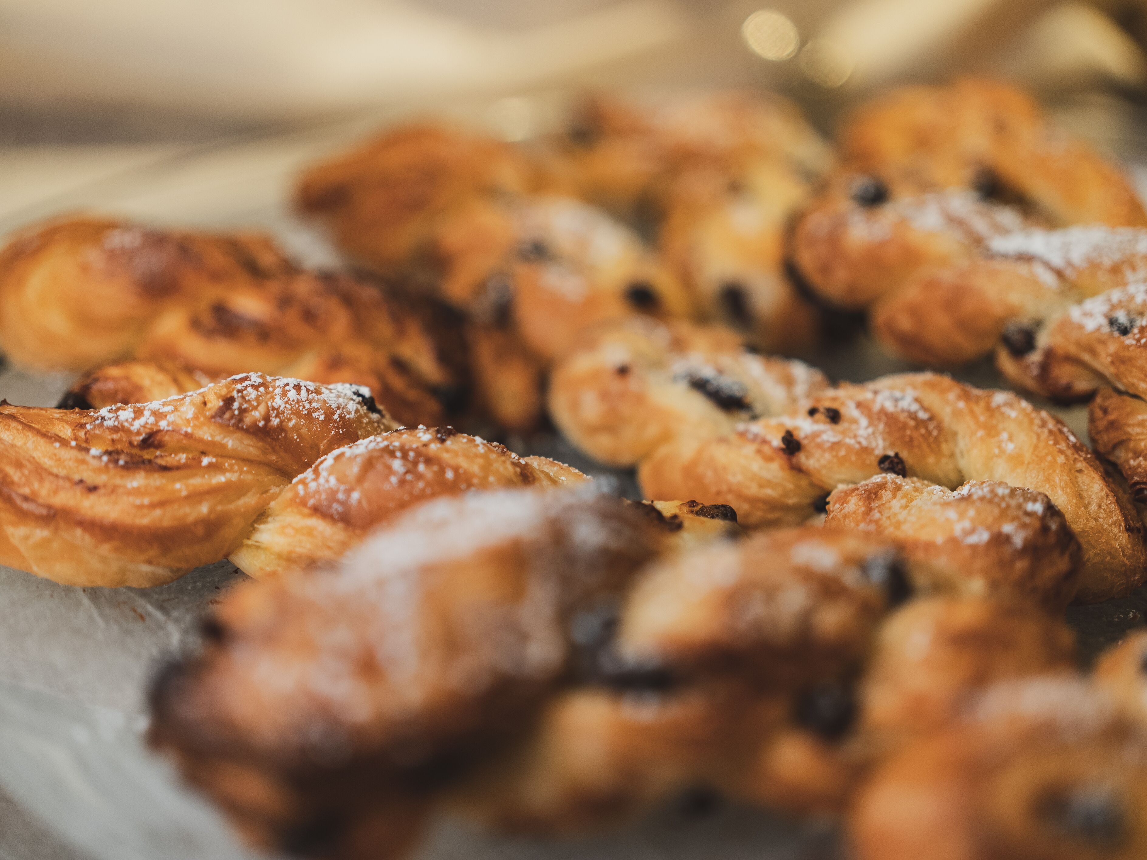 A tray of assorted pastries, including croissants and muffins, with visible sugar and fruit pieces.
