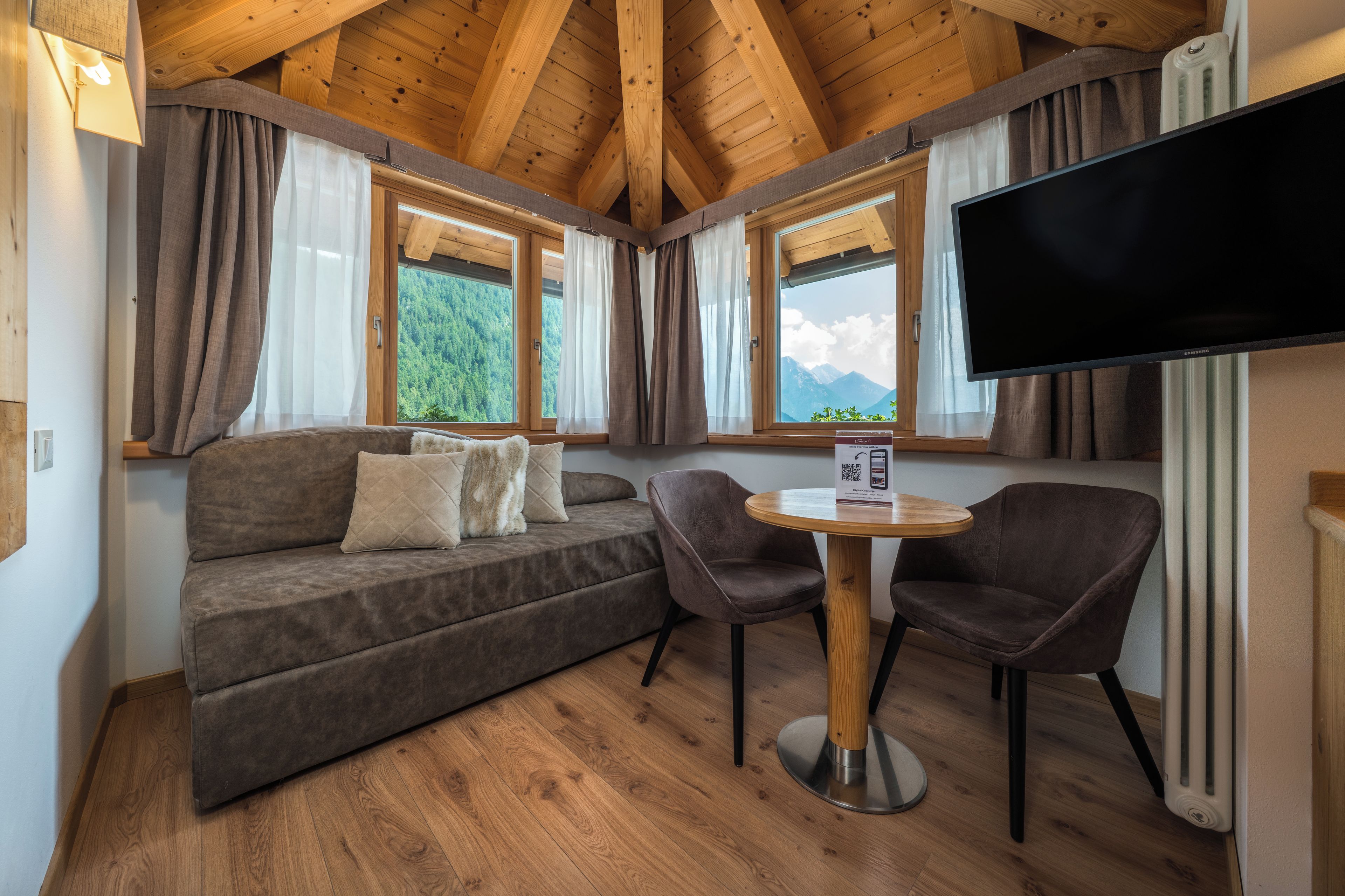 A cozy room with a sofa, two chairs, a table, and a TV.