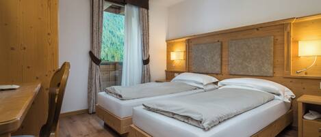 A double bed with a wooden headboard, a bedside table with a lamp, and a window with curtains.