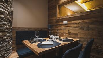 Un tavolo da pranzo in legno con una panca imbottita nera, una parete in pietra e un soffitto in legno con un lucernario.