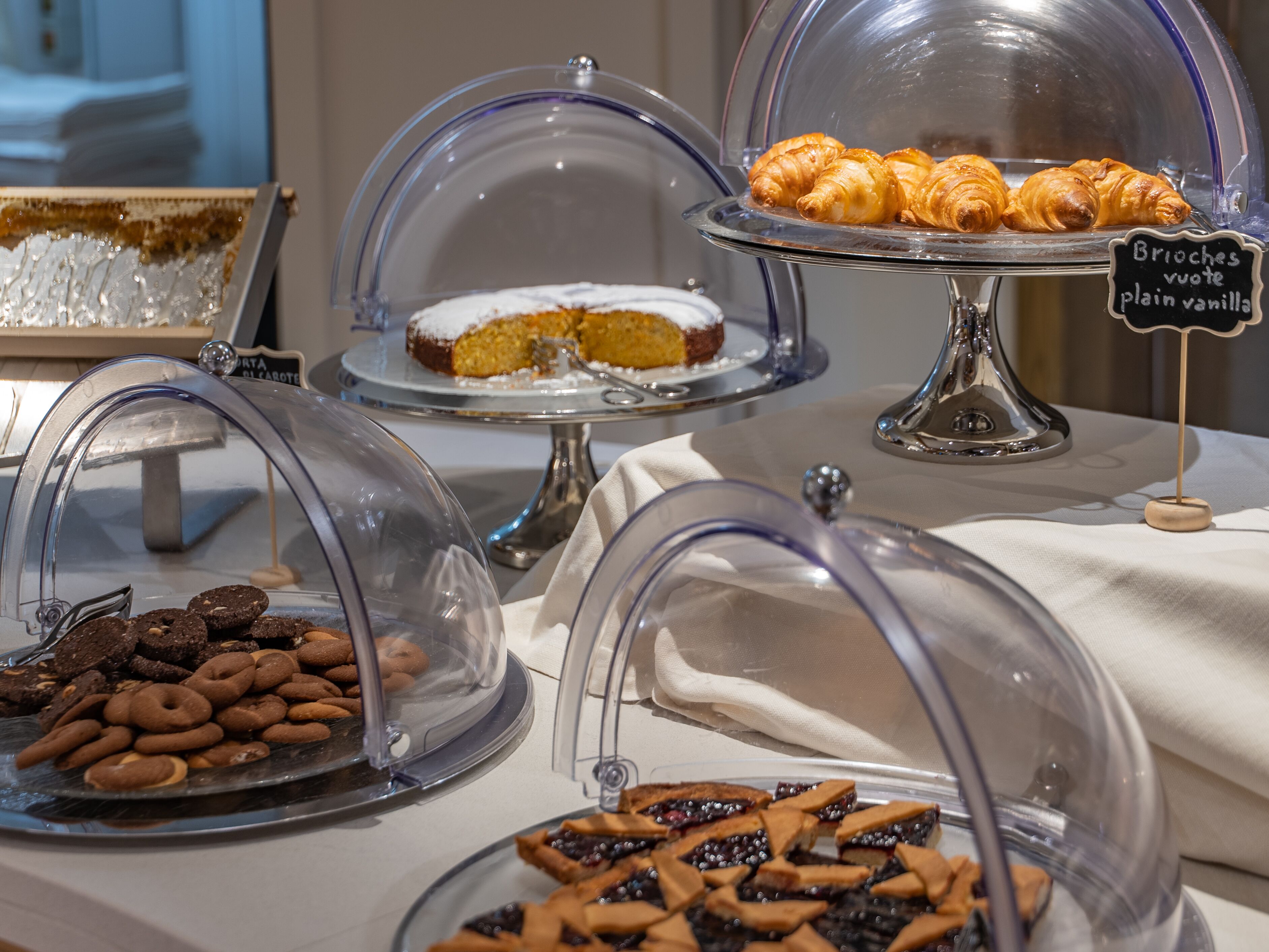 A buffet with various pastries and desserts under glass domes.