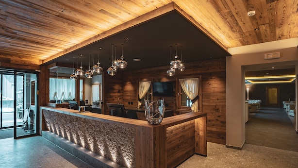 Un área de recepción con techo de madera, mostrador de mármol e iluminación colgante.