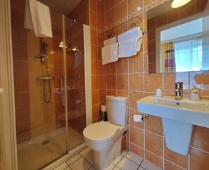 A bathroom with a glass-enclosed shower, a toilet, and a sink with a mirror above it. - Hôtel Vauban (Brest)