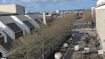 A city street with a bus lane, parked cars, and pedestrians.