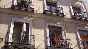 Un edificio de varios pisos con balcones, ventanas con contraventanas y una puerta visible.