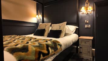 A bedroom with a bed, two wall-mounted lamps, a nightstand, and a decorative wall piece.