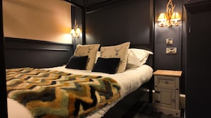 A bedroom with a bed, two wall-mounted lamps, a nightstand, and a decorative wall piece. - The Original Rosslyn Inn (Roslin)