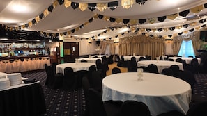 A banquet hall with round tables, black chairs, and a bar area. - The Original Rosslyn Inn (Roslin)