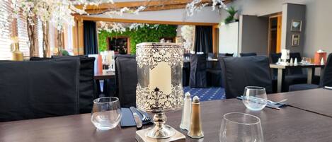 Una mesa de comedor con un centro de mesa decorativo, copas transparentes y cubiertos.