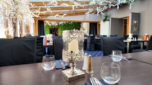 Une table à manger agrémentée d’un centre de table décoratif, de verres transparents et de couverts.