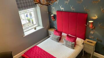 A bedroom with a bed, a nightstand, a window with blinds, and a wall with deer decals.