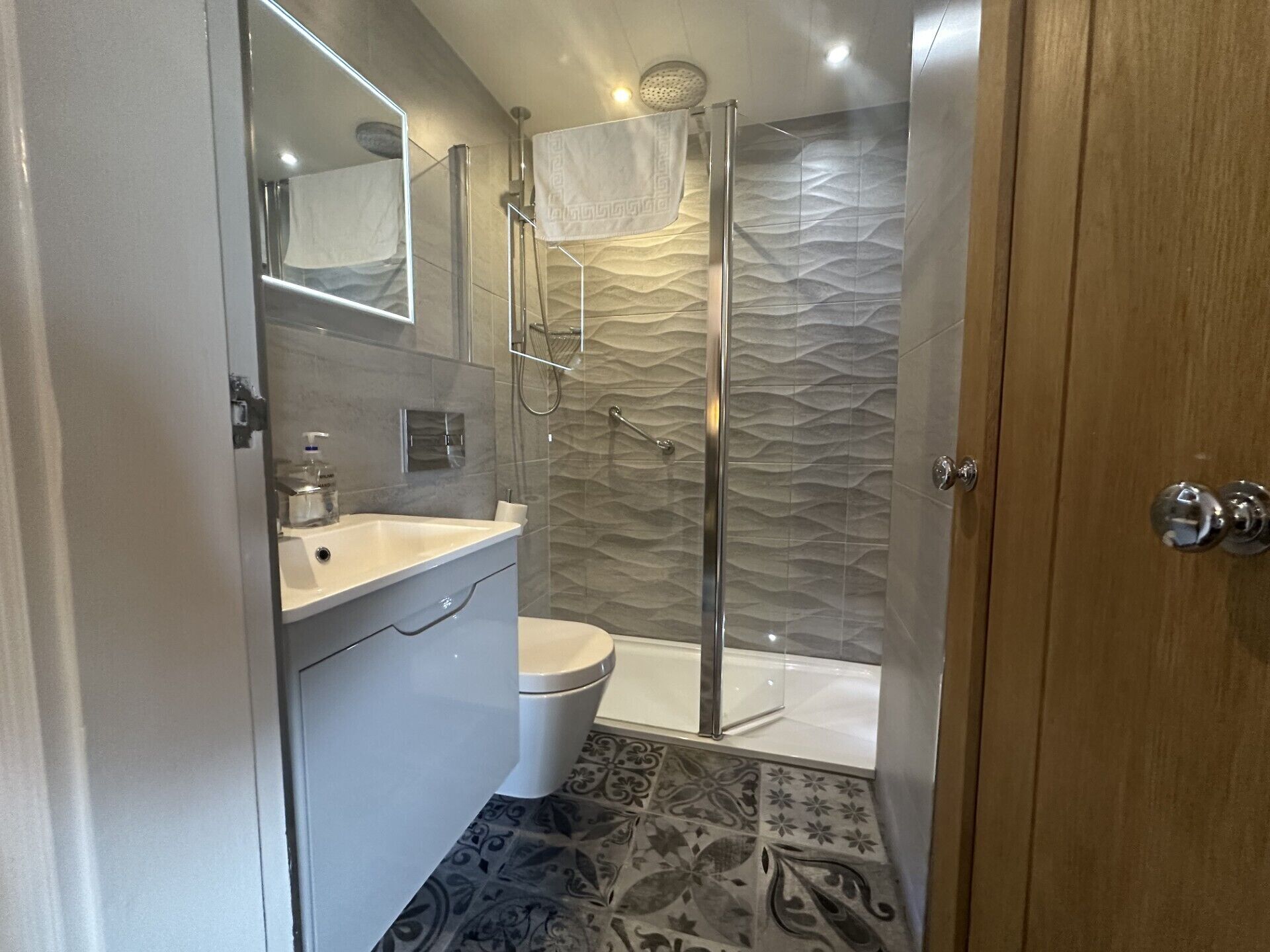 A modern bathroom with a glass-enclosed shower, a white sink, and a toilet.