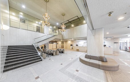 A spacious lobby with a grand staircase, seating area, and a reception desk.