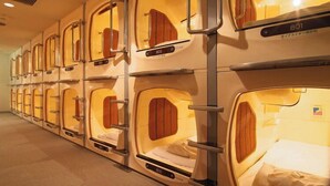 A row of compact, individual sleeping cabins with numbers on the doors, indicating a private room arrangement. - Golden Time Takamatsu (Takamatsu)