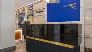 Balcão de recepção com bancada de mármore e um letreiro azul em cima.