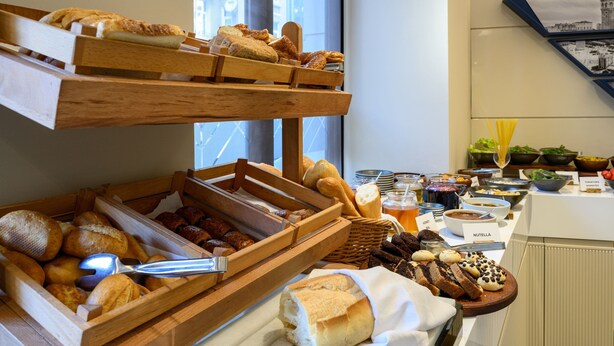Buffet com diversos pães, pastelaria e uma faca em um prato.