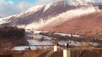 Montanha com picos nevados e um vale com edifícios.