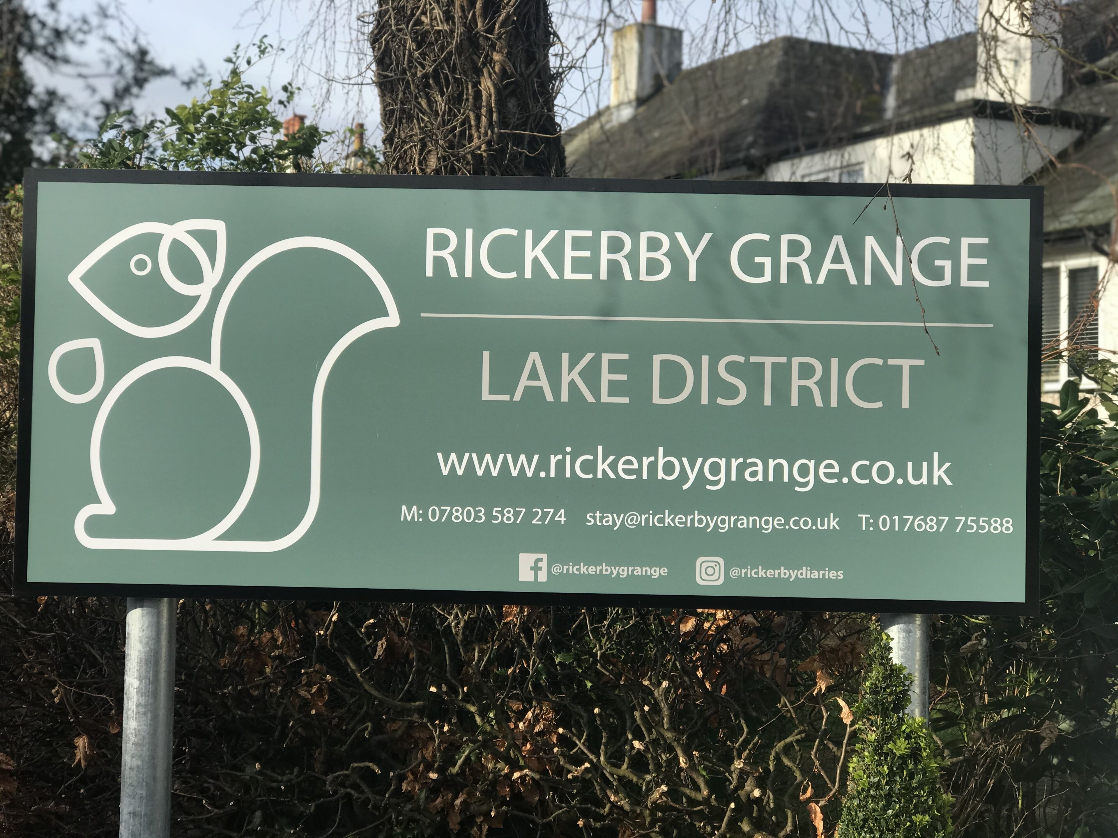A sign for Rickerby Grange Lake District with contact information and website URL.