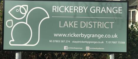 A sign for Rickerby Grange Lake District with contact information and website URL.
