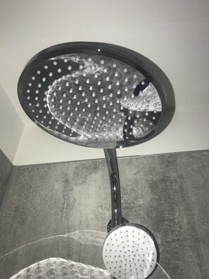 A showerhead with multiple round nozzles, mounted on a wall with a textured surface.