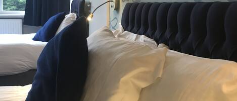 Een hotelkamer met een bed, voorzien van een donker hoofdeinde en witte beddengoed.