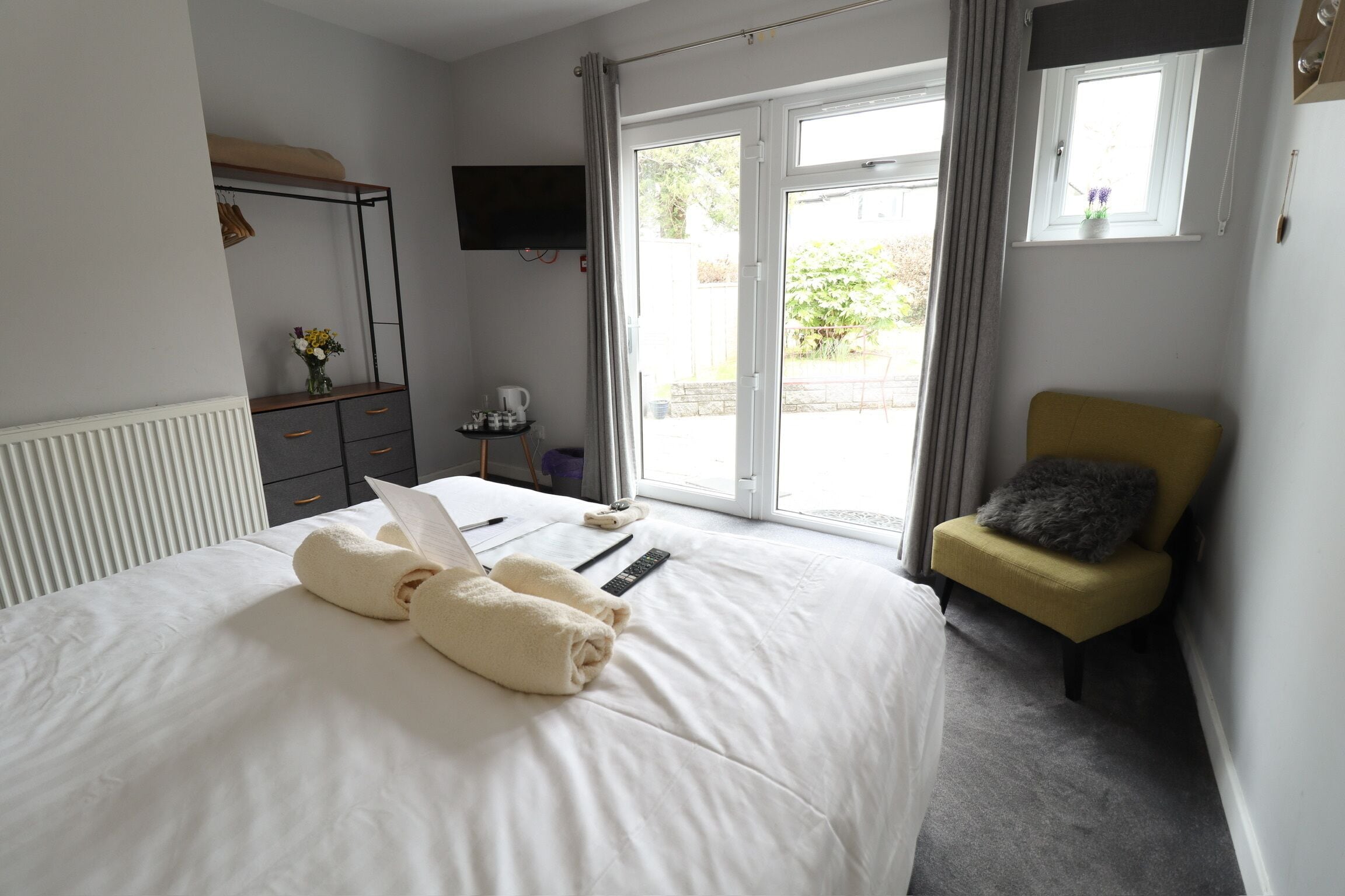 Une chambre à coucher avec un lit, une chaise, une télévision et une fenêtre.