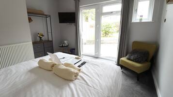 Une chambre à coucher avec un lit, une chaise, une télévision et une fenêtre.